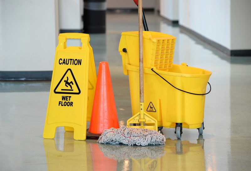 Caution sign with mop and bucket on office floor